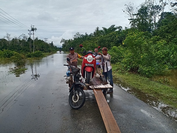 Jalan Terhalang Banjir, Polisi Bantu Warga Seberangkan Sepeda Motor