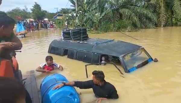 TERJEBAK: Mobil penumpang umum jenis L-300 terjebak banjir setelah nekat menerobos banjir di jembatan perbatasan Gampong Kliet – Beurandang, Ranto Peureulak, Aceh Timur, Senin (7/11). Waspada/Ist.