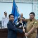 Kadinsos Aceh Besar, Bahrul Jamil, SSos, MSi (kanan) menyerahkan pataka kepada Zarwatun Niam yang terpilih sebagai Ketua Karang Taruna Aceh Besar masa bakti 2022-2027. (Waspada/Ist)