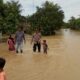 KAPOLSEK Besitang AKP Trisno Carlos Sihite bersama Kanit Intel Aiptu Leo S Surbakti mengevakuasi bocah dari arus banjir di Dusun Pantai Pulau. Waspada.id/Asrirrais