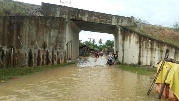 ARUS banjir, Kamis (3/11) pagi, mengalir deras dari bawah terowongan jalur kereta api di Lingk VIII menuju Lingk IX, Kel. Bukit Kubu, Kec. Besitang. Waspada.id/Asrirrais