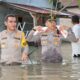 Kapolres Batubara AKBP Jose DC Fernandes bersama jajarannya mengarungi banjir, bawakan bantuan kepada warga terdampak banjir di Dusun I Desa Lubuk Cuik. (Waspada/Ist)