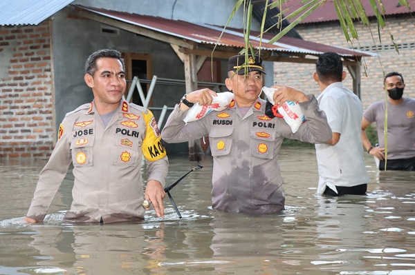 Kapolres Batubara AKBP Jose DC Fernandes bersama jajarannya mengarungi banjir, bawakan bantuan kepada warga terdampak banjir di Dusun I Desa Lubuk Cuik. (Waspada/Ist)