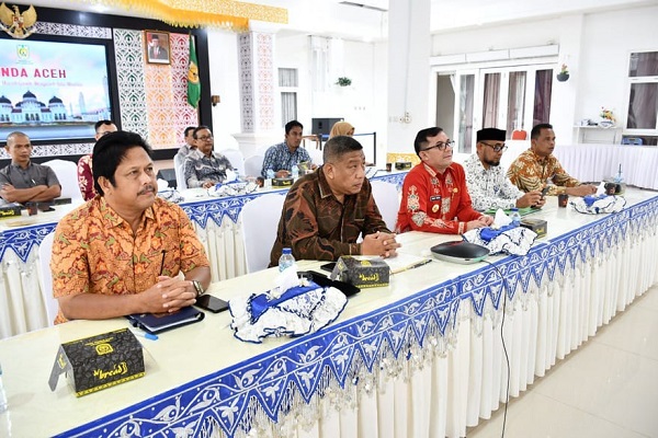 Pj.Wali Kota Banda Aceh Bakri Siddiq (baju merah) sedang mengikuti acara penganugerahan via zoom meeting dari pendopo wali kota Banda Aceh, Kamis (08/12/22). (Waspada/T.Mansursyah)