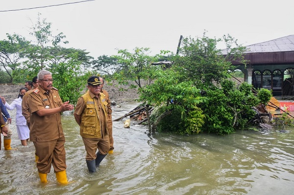 WAKIL Bupati Deliserdang HMA Yusuf Siregar mendengarkan penjelasan Camat Beringin Iskandar Sayuti Siregar ketika meninjau kondisi banjir di Dusun Mesjid, Desa Beringin, Kecamatan Beringin, Senin (12/12).- (Waspada/Khairul K Siregar/B)