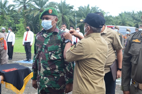 Plt Bupati Palas drg Ahmad Zarnawi Pasaribu CHt MM MSi, menyematkan pita tanda operasi secara simbolis kepada personel pasukan OPS Lilin Toba 2022, di Mapolres Palas, Kamis (22/12). Waspada/Ist