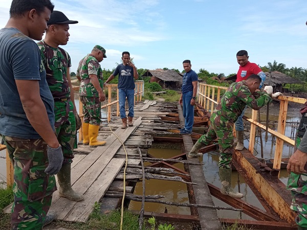 Personel Koramil Banda Mulia jajaran Kodim 0117/Aceh Tamiang bersama warga memperbaiki jembatan kayu yang rusak parah di Kampung Alur Nunang, Kec Banda Mulia, Kab Aceh Tamiang. (Waspada/Yusri).