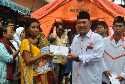 ANGGOTA DPRD Sumut H Hanafi (kanan) menyerahkan bantuan uang tunai kepada salah seorang warga yang terdampak kebakaran di Kelurahan Tegal Sari III, Kecamatan Medan Area, Kota Medan, Minggu (22/1). Waspada/ist
