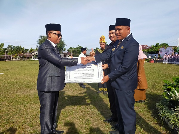 Pj Bupati Abdya Darmansah, menyerahkan hibah aset tanah milik Pemkab, juga bangunan kepada Kakankemenag Abdya Salman Alfarisi, dalam peringatan HAB ke 77 di lapangan Pantai Perak Susoh, Selasa (3/1/2023). Waspada/Syafrizal