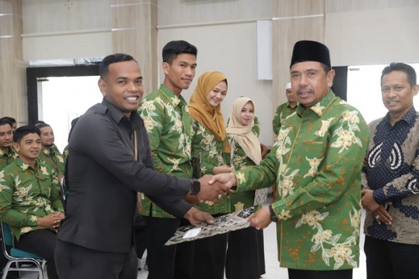 Kakanwil Kemenag Aceh DR Iqbal (kanan) menyerahkan secara simbolis SK kepada salah seorang pramubhakti di Aula Kanwil setempat, Rabu (18/01/23). (Waspada/T.Mansursyah)
