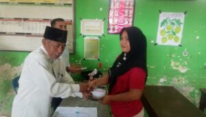 SALAH seoorang wali murid diabadikan saat menerima penyerahan uang bantuan PIP dari Kasek SDN 056036 Tugino. Waspada/Asrirrais