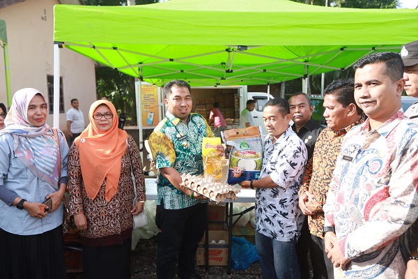 Pj Bupati Aceh Besar, Muhammad Iswanto, ikut membagikan pangan murah bagi masyarakat yang digelar Pemkab Aceh Besar dengan Perum Bulog Divre Aceh di Gampong Gani. (Waspada/Zafrullah)