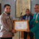 Wakil Rektor III USK, Prof. Mustahil Yahya (kanan), memberikan piagam kepada Pj Bupati Aceh, Muhammad Iswanto, sebagai tanda terima kasih atas kepedulian Pemkab Aceh Besar yang menerima mahasiswa KKN di daerah itu. (Waspada/Zafrullah)
