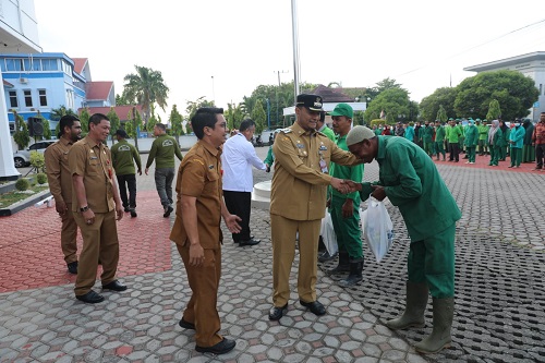 Penjabat Wali Kota Lhokseumawe, Dr Drs Imran M.Si secara simbolis menyerahkan 350 paket bantuan beras dan sertifikat penghargaan kepada pekerja kebersihan Dinas Lingkungan Hidup dan Kebersihan dihalaman Kantor Walikota setempat, Senin (13/3). Waspada/Zainuddin Abdullah