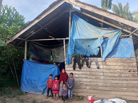 Keluarga Usman Nurdin, 43, berdiri di depan gubuk mereka, Gampong Geudumbak, Kecamatan Langkahan, Aceh Utara. Rumah beratap daun rumbia ini, ditempati anak-anak dan lansia, Senin (27/3). (Waspada/ist)