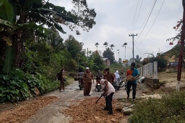 H. Maralohot Siregar, Camat Sosopan bersama staf menimbun jalan provinsi yang rusak dan berlubang di Desa Sosopan untuk mengurangi risiko kecelakaan. (Waspada/Idaham Butar Butar/B)