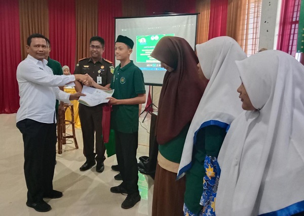 Staf Ahli Bidang Perekonomian, Keuangan dan Pembangunan, Ir Makmun MT, menyerahkan buku sadar hukum kepada siswa saat mengikuti penyuluhan hukum Program Jaksa Masuk Sekolah (JMS) di Gedung Dekranasda, Rabu (8/3). (Waspada/Zafrullah)