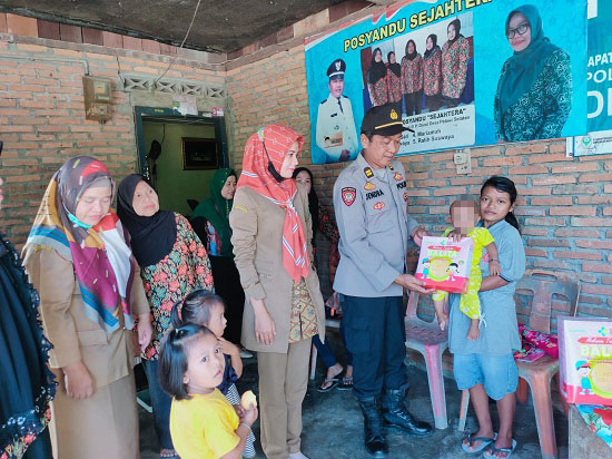 Wakapolsek P.Brandan Iptu Rajendra saat menyerahkan makanan Balita di giat Posyandu di Desa Pelawi Selatan Kec.Babalan Kab.Langkat, Selasa (4/4). Waspada/ist