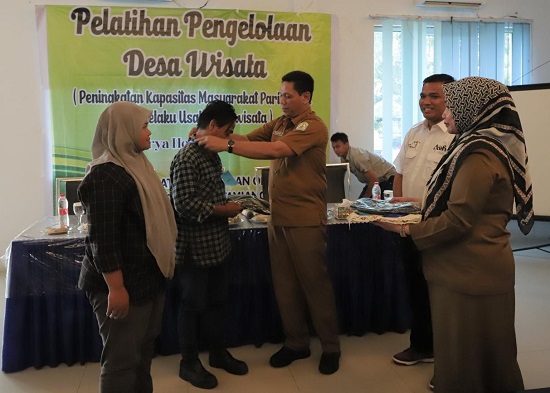 Asisten Pemerintahan, Muslizar saat mengalungkan tanda peserta secara simbolis pada pembukaan pelatihan manajemen pengelolaan desa wisata untuk Pokdarwis di Hotel Grand Arya, Senin (15/5). Waspada/Yusri