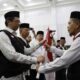 Irjen Kemenag RI Faisal Ali Hasyim menyerahkan Bendera Merah Putih kepada petugas kloter usai melepas calon jamaah haji Kloter 01 di Aula Embarkasi Haji Aceh, Selasa (23/05/23) malam. (Waspada/T.Mansursyah)