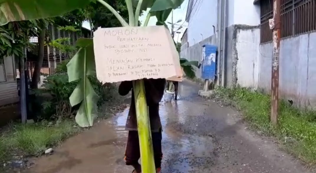 SEORANG warga membawa Pohon Pisang untuk ditanam di badan jalan di Jl. Platina VII D Lorong III Lingkungan III Kelurahan Titipapan Kecamatan Medan Deli, Minggu (21/5). Waspada/Andi Aria Tirtayasa