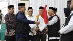 Kakanwil Kemenag Aceh yang juga Ketua PPIH Embarkasi Aceh Drs. Azhari menyerahkan Bendera Merah Putih kepada petugas saat pelepasan kloter 12 yang merupakan kloter gabungan terakhir Aceh di Asrama Haji Banda Aceh, Senin (19/06/23). (Waspada/T.Mansursyah)