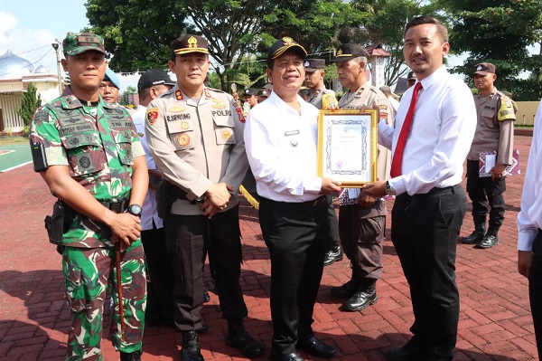 Bupati Simalungun Radiapoh H Sinaga, didampingi Kapolres Simalungun AKBP Ronald FC Sipayung dan Dandim 0207/Sml Letkol Inf Hadrianus Yossy menyerahkan piagam penghargaan kepada Kasat Reskrim AKP Rachmat Aribowo, di halaman Mapolres Simalungun, Rabu (21/6).(Waspada/ist).