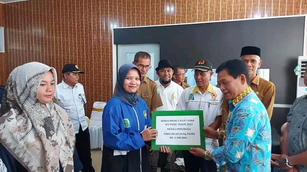 Pj. Bupati Simeulue Ahmadliyah di dampingi Sekda Asluddin menyerahkan bonus kepada salah seorang peraih perunggu PORA di Pidie Tahun 2022. Senin (27/6). Waspada/Ist.