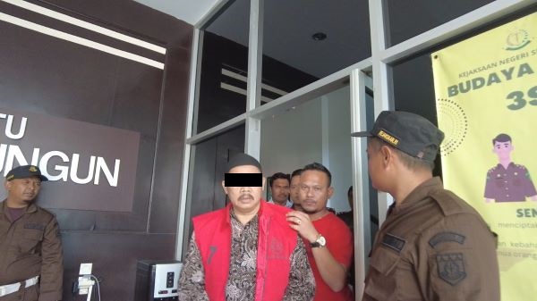 Oknum PM mantan Pangulu Bahung Kahean, menggunakan rompi merah saat digiring dari kantor Kejari Simalungun, Jumat (21/7).(Waspada/ist).