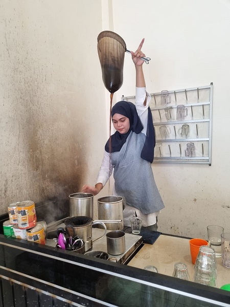 Wulan pengusaha warung kopi yang sukses sedang mengangkat saring kopi saat dijepret waspada.id. (Waspada/T. Zakaria)