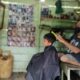 Sutan Siregar, penyandang cacat disabilitas saat memangkas rambut pelanggannya. (Waspada/Syarif Ali Usman)