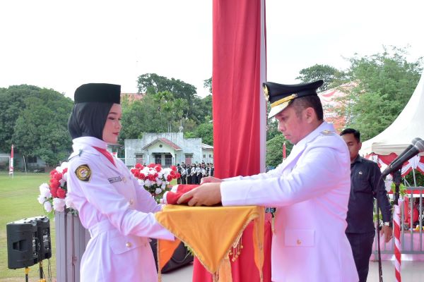Pembawa Baki Adinda Suci Aufa siswi SMA Negeri 1 Sabang menerima bendera dari Penjabat Wali Kota Sabang Reza Pahlevi selaku Inspektur Upacara. (Waspada/ist.)