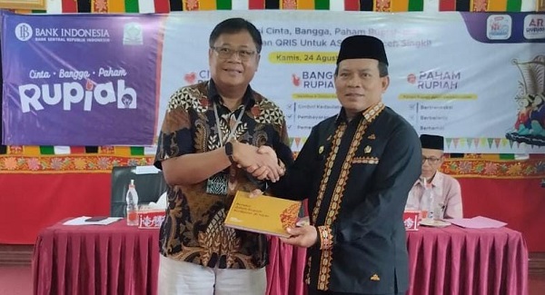 KPW BI Aceh Rony Widijarto menyerahkan buku petunjuk Qris kepada Plh Asissten Administrasi Umum Edy Widodo, saat sosialisasi Gerakan Cinta Rupiah, di Oprrom Kantor Bupati, Kamis (24/8). WASPADA/Ariefh