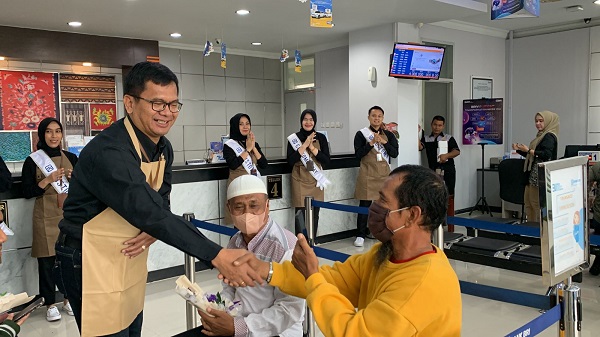 Branch Manager BRI BO Tanjungbalai, Heldin Suranta Tarigan didampingi Asisten Manager Operasional dan Layanan (AMOL), Ahmad Fauzi memberikan coklat dan kue kepada nasabah di Hari Pelanggan Nasional 2023. Waspada/Ist