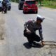 Personel Satlantas Polres Aceh Timur, memperlihat lubang di badan jalan negara Banda Aceh - Medan, persisnya di Gampong Alue Bu Tuha, Peureulak Barat, Aceh Timur, Senin (2/10). Waspada/H. Muhammad Ishak