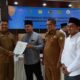 Sekdakab Aceh Besar, Drs Sulaimi, MSi menyerahkan sertifikat tanah wakaf yang kepada salah seorang nazhir dalam acara yang berlangsung di Aula Baharuddin Lopa Kejari Aceh Besar, Selasa (17/10). (Waspada/Zafrullah)