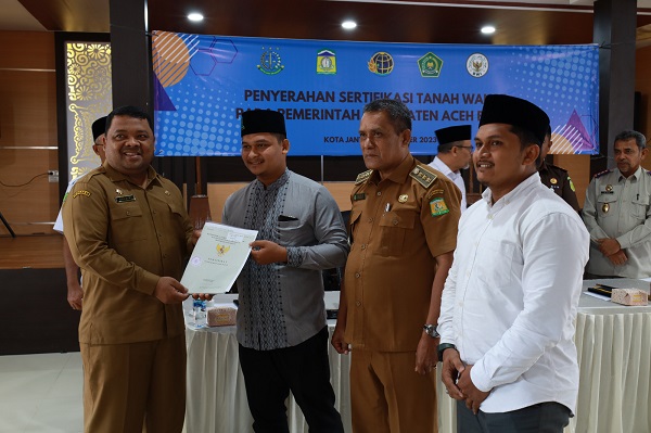 Sekdakab Aceh Besar, Drs Sulaimi, MSi menyerahkan sertifikat tanah wakaf yang kepada salah seorang nazhir dalam acara yang berlangsung di Aula Baharuddin Lopa Kejari Aceh Besar, Selasa (17/10). (Waspada/Zafrullah)