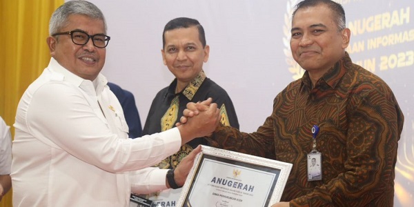 Sekda Aceh, Bustami Hamzah, saat menyerahkan penghargaan kepada pemenang Anugerah Keterbukaan Informasi Publik Tahun 2023 yang diselenggarakan Komisi Informasi Aceh di Aula Amel Convention Hall, Banda Aceh, Rabu (6/12). (Waspada/Zafrullah)