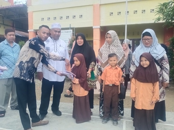 Maulizar Zikri,anggota DPRK Aceh Tamiang saat menyerahkan bantuan pakaian seragam sekolah untuk murid SDN 2 Tualang Cut,Kec Manyak Payed,Jumat (1/12).(Waspada/Yusri)