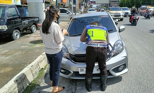 Personel Sat Lantas Polres Pematangsiantar mengenakan Tilang terhadap pengendara mobil pribadi yang parkir secara sembarangan di zona larangan di Jl. Sutomo, Jumat (8/12).(Waspada-Ist).