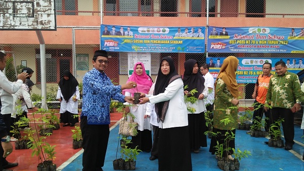 Ketua PGRI Banda Aceh Zulfikar menyerahkan pohon kepada Kepala Sekolah dalam rangka HUT Ke 78 PGRI dan HGN Tahun 2023, di Sekretariat PGRI Banda Aceh di SMA Negeri 15 Adidarma Banda Aceh, Kamis (30/12/23). ( Waspada/T.Mansursyah)