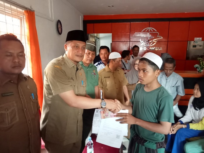 Kadis Sosial Palas, H Achmad Fauzan Nasution menyerahkan bantuan sosial Kemensos RI kepada anak yatim atau piatu di Kantor Pos Sibuhuan, Senin (18/12). Waspada/Muhammad Satio)