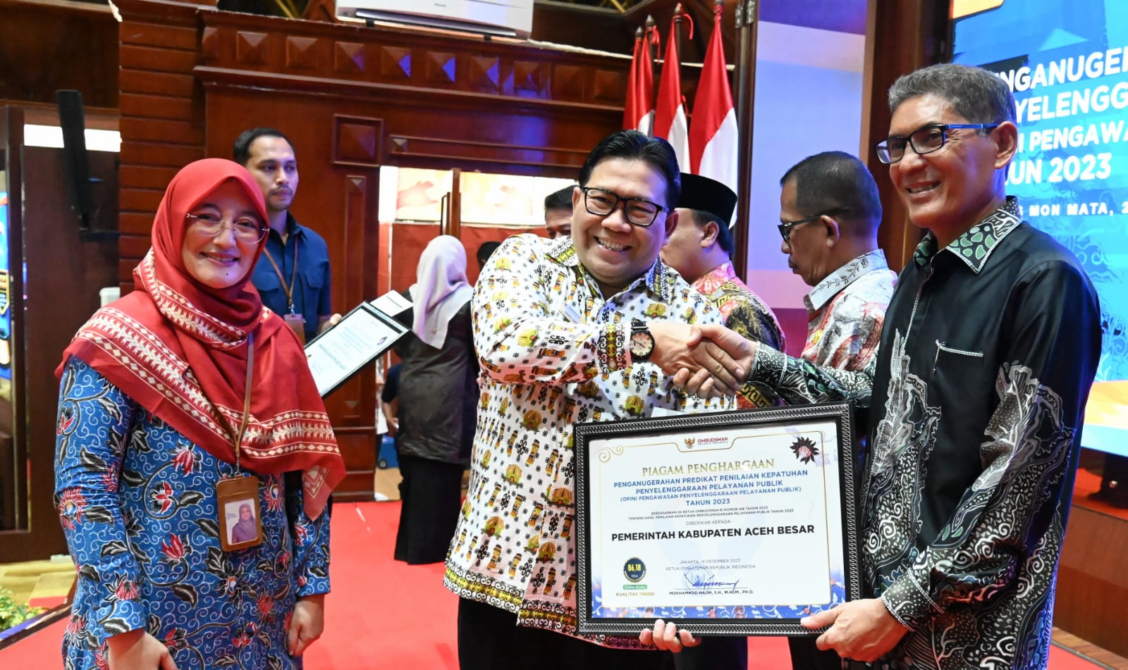 Pimpinan Ombudsman RI, Dadan S. Suharmawijaya menyerahkan Piagam Penghargaan dan Sertidikat Penganugerahan Predikat Penilaian Kepatuhan Penyelenggaraan Pelayanan Publik kepada Asisten III Pemkab Aceh Besar, Jamaluddin, S.Sos, MM di Ajong Mon Mata, Banda Aceh, Kamis (25/1). (Waspada/Ist)
