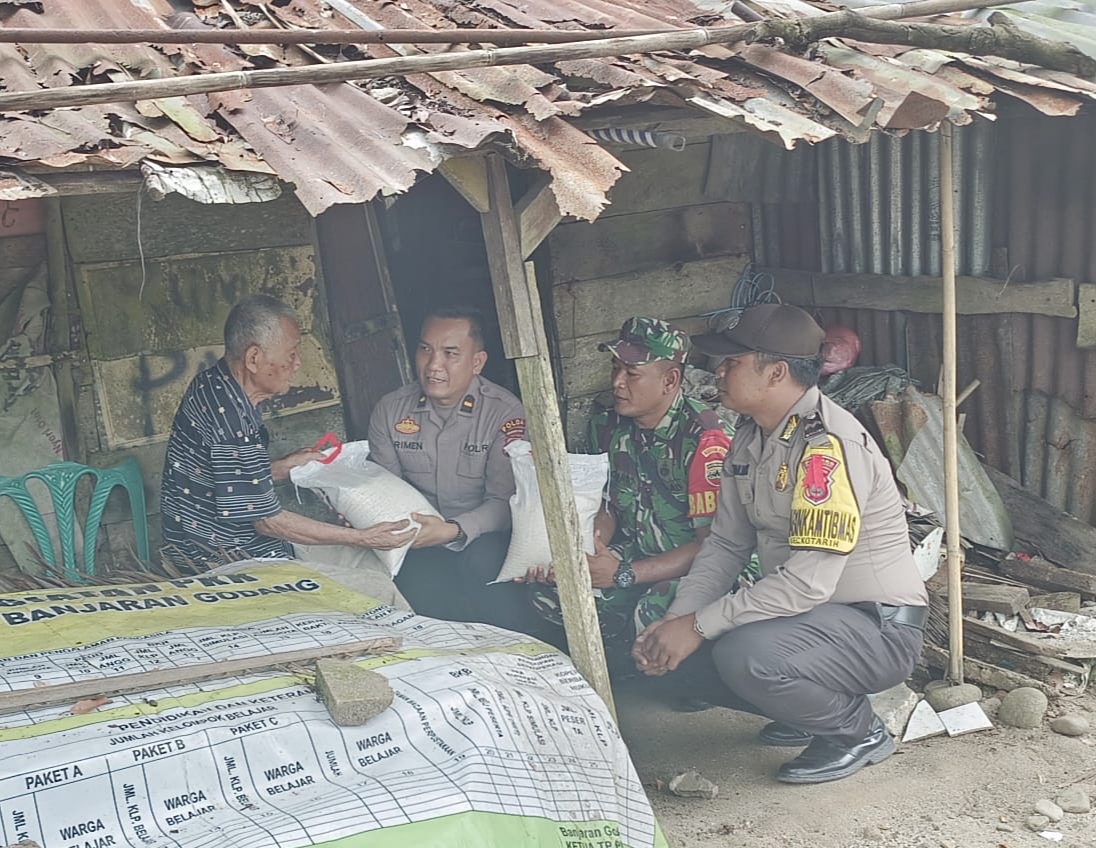Kapolsek Kotarih Iptu Mula Purba diwakili Wakapolsek Ipda Brimen bersama personel Koramil 17/Kotarih saat menyerahkan bantuan kepada warga miskin, Jumat (9/2) kemarin di Dusun II Desa Banjaran Godang Kec. Kotarih. ( Waspada/Ist)