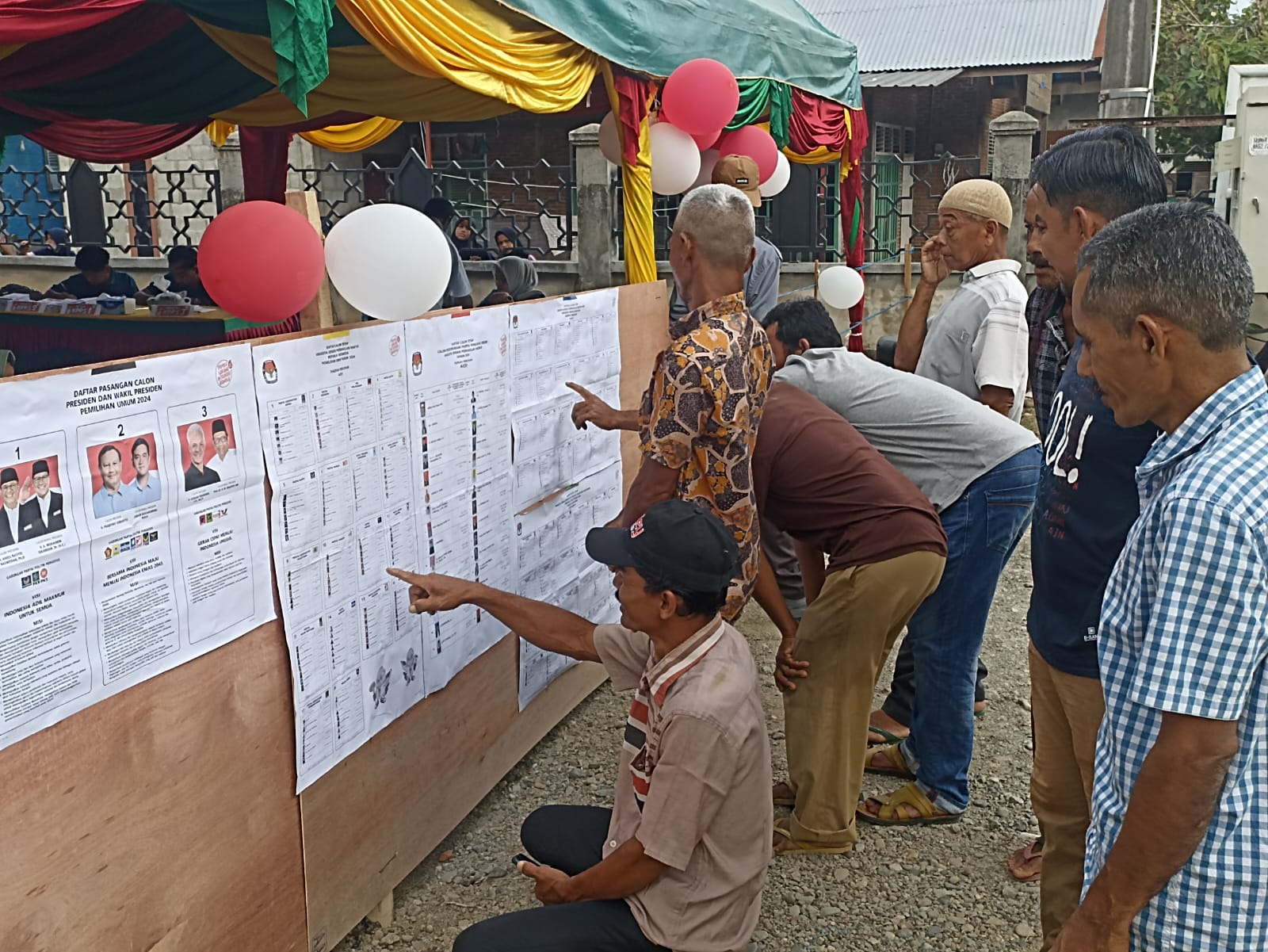 Para pemilih di Gampong Lam Ara Eungkit, Kecamatan Kuta Malaka, Aceh Besar, melihat daftar caleg yang ditempelkan sebelum melakukan pencoblosan, Rabu (14/2). (Waspada/Ist)