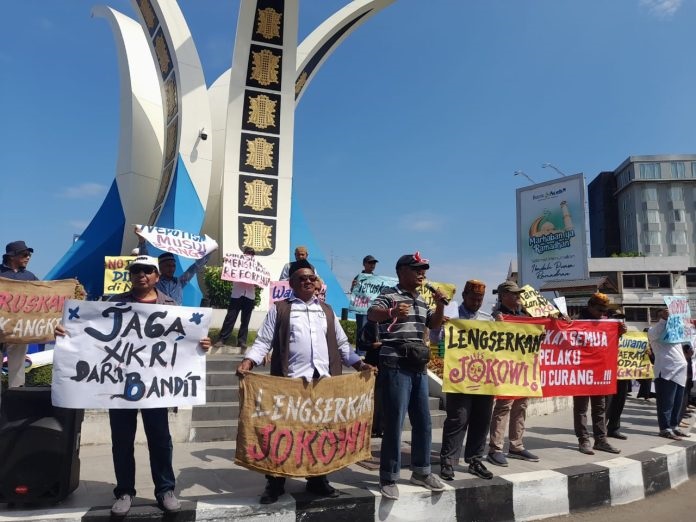 Massa aksi dengan membawa spanduk dan poster di bundaran Simpang Lima Banda Aceh, Rabu (20/03/24). (Waspada/T.Mansursyah)