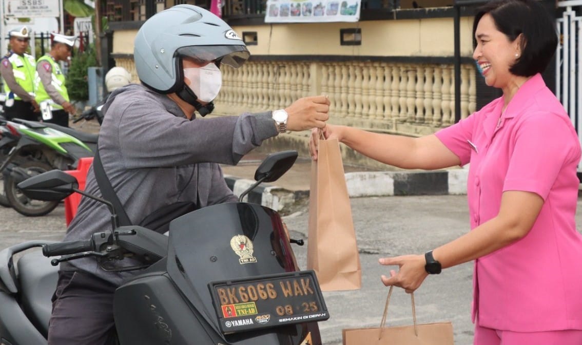 Ketua Bhayangkari Cabang Polres Pematangsiantar Ny. Sandra Yogen (kanan) membagikan makanan berbuka puasa secara gratis kepada pengendara yang melintas di depan Mapolres, Jl. Jend. Sudirman, Rabu (20/3) sore.(Waspada-Ist).