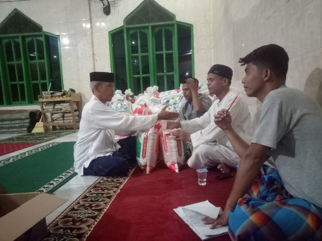 CHAERUL Anwar, S.Ag (kiri) mewakili Keluarga Besar DMT Subulussalam serahkan zakat fitrah puluhan jiwa DMT diterima Imam Masjid, Juhri Tumangger, Minggu (7/4) malam. (Waspada/Khairul Boangmanalu)