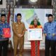 Juredah, guru pedalaman Leuser saat memegang Penghargaan Peduli Pendidikan didampingi Pj Bupati Syakir (kiri), dan Kepala Dinas PPKB Budi Afrizal, SKM, MKM (kanan). Waspada/Seh Muhammad Amin