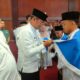 Pj. BUPATI Deliserdang Ir. Wiriya Alrahman, MM, didampingi Ketua IPHI Deliserdang H.Ali Tambunan menyematkan syal kepada Muhammad Habib Rizky Daulay calon jamaah haji termuda usai manasik haji akbar dan tepung tawar di Grha Bhineka Perkasa Jaya, Rabu (15/5). (Waspada/Khairul K Siregar/B)